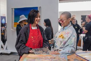 Demi Lovato and Raven Symoné look at a painting in a busy art gallery, in 'Child Star.'