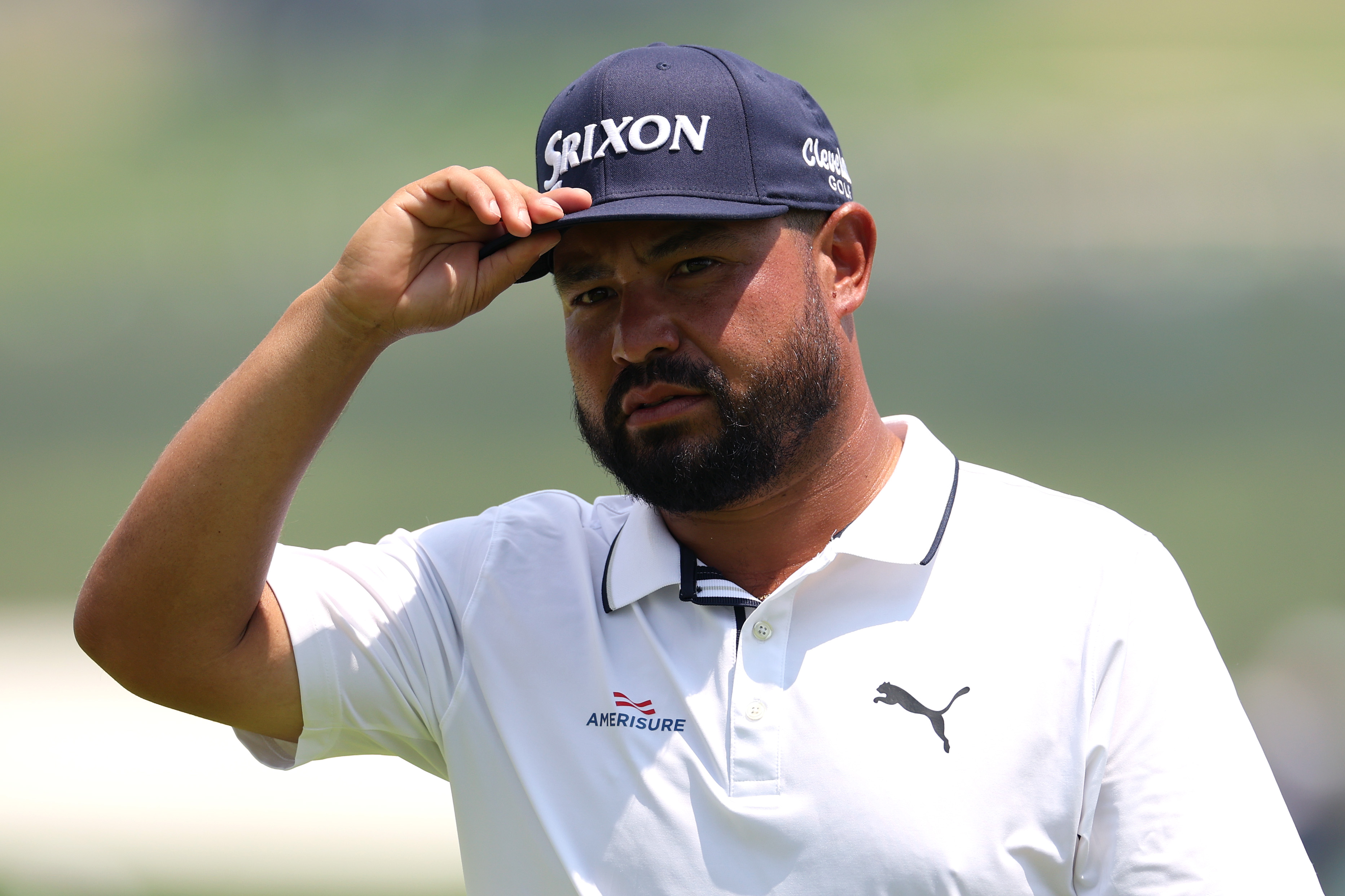 JJ Spaun touches his hat after walking off the green