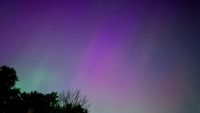 photo of the northern lights, showing light green and purple lights in a dark night sky