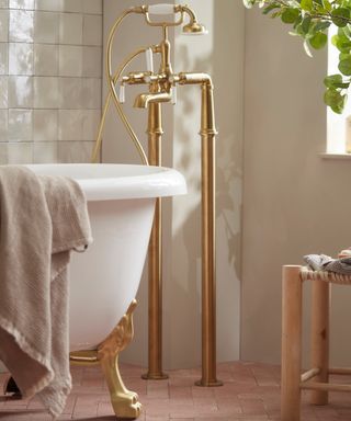 close up detail of gold floor mounted bath taps