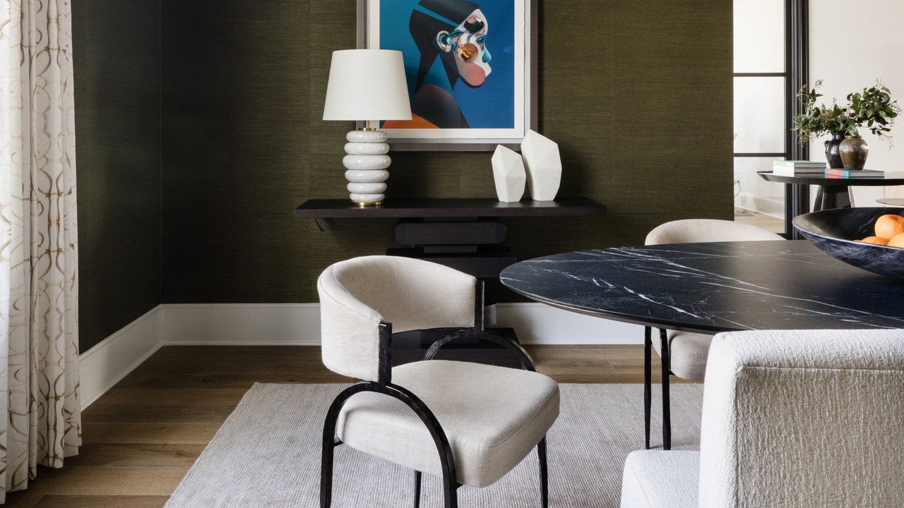 dining room with green grasscloth wallpaper, console table with art, patterned curtains, black marble dining table and boucle chairs