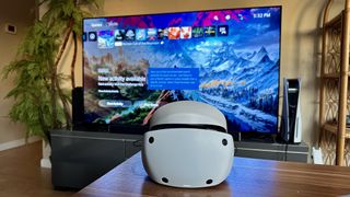 Sony PS VR2 sitting in front of TV showing PS5 main menu.
