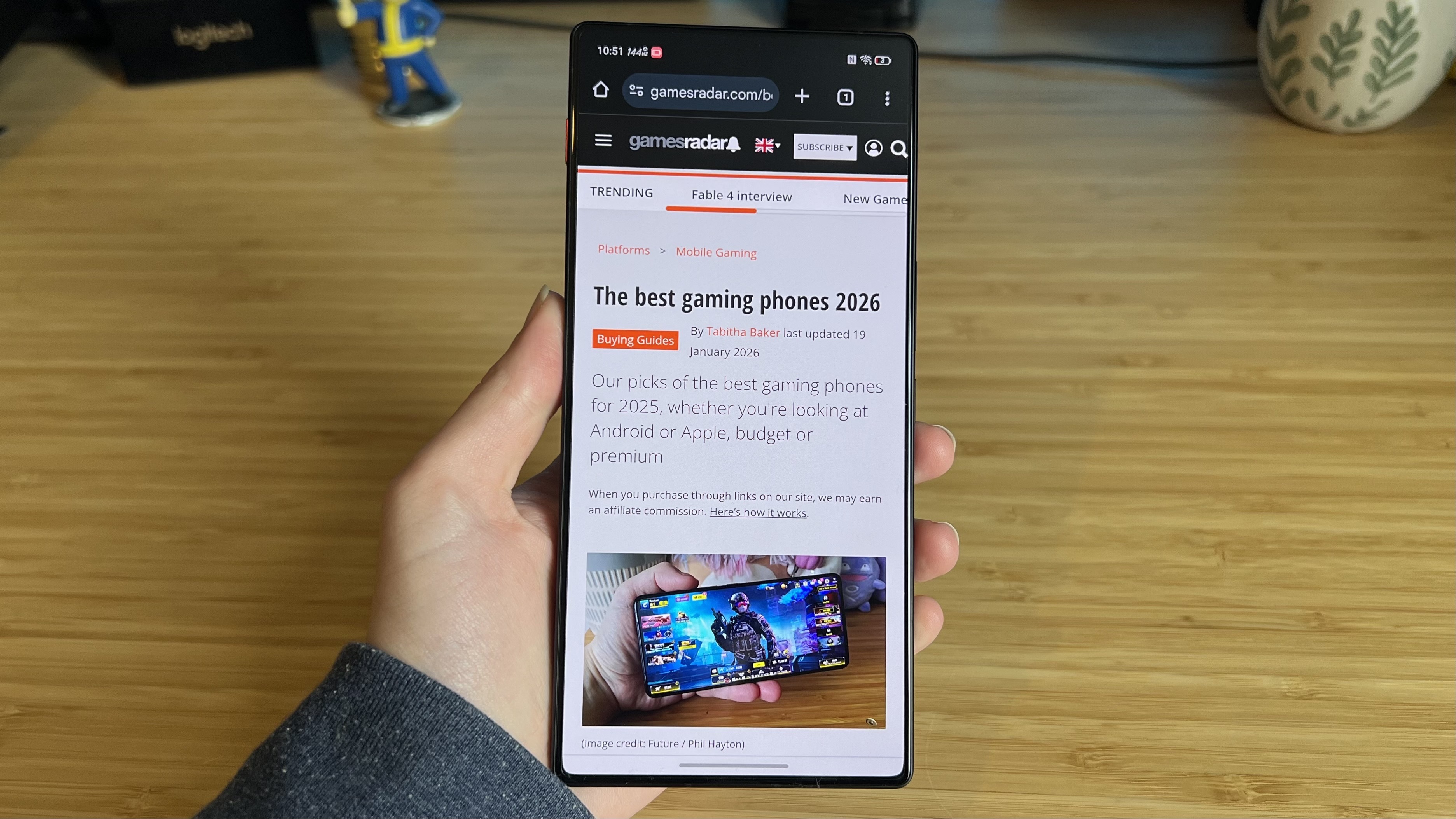 RedMagic 11 Air gaming phone running web browser in-hand against a wooden desk