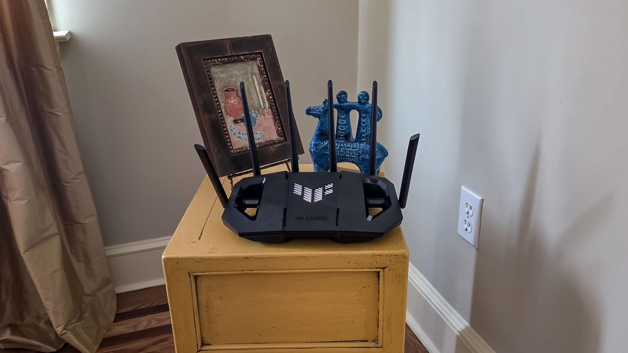 An Asus TUF Gaming BE6500 router on a small table.