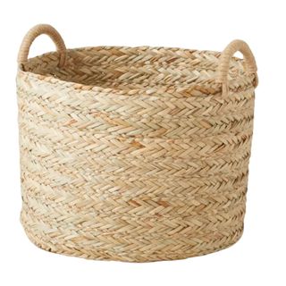 A circular braided grass storage basket with integrated handles