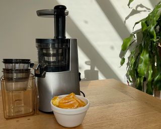 Hurom H-AA slow juicer with bowl of fresh orange segments
