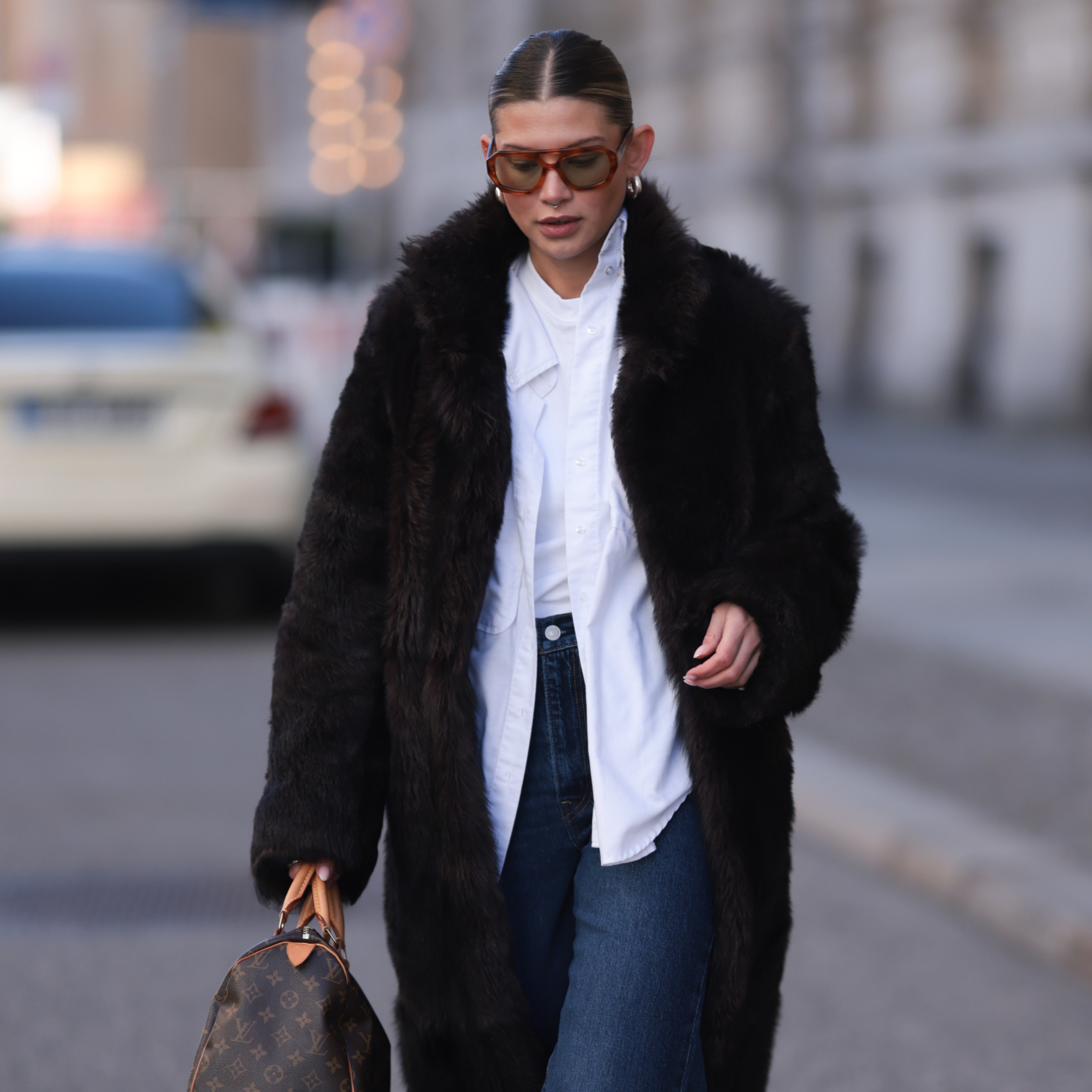 woman wearing a faux fur coat, a button down, and jeans