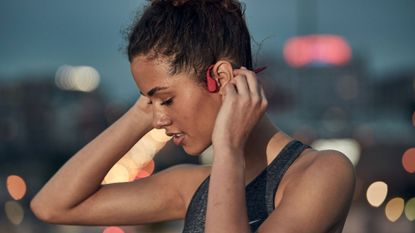 best bone conduction headphones: A woman wearing Shokz OpenRun headphones