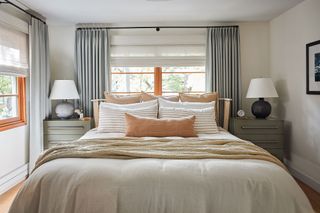 double bed in room with white walls and grey curtains matching bedside tables and lamps