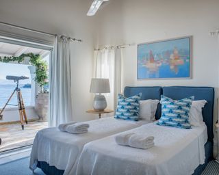 A twin bedroom at a Corfu villa with blue printed cushions from Ottoline and a sea view