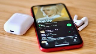 the Spotify app open on a phone with some AirPods