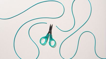 Scissors cut through a swirling green cord.