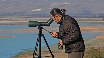 man using a spotting scope in an outdoor location