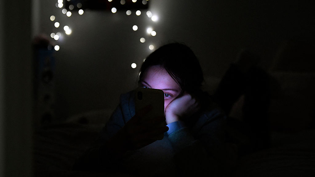 A woman scrolling on her phone in bed