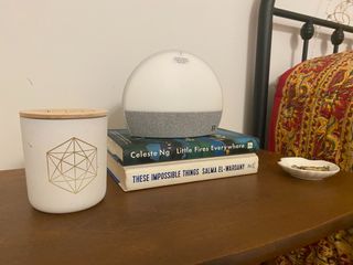 Hatch Restore on a nightstand with books and a candle