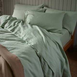 Piglet in Bed Sage Green Bedtime Bundle on a bed against a white wall.