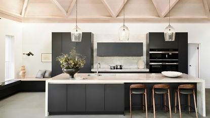 A black kitchen with white counters, with minimalist decor 