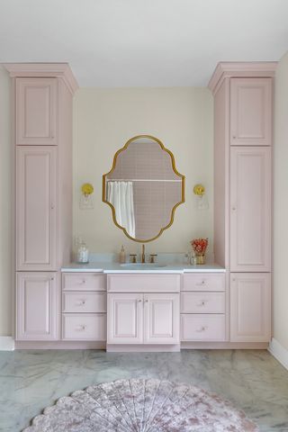 pink bathroom cabinets in various sizes, gold mirror, marble floor