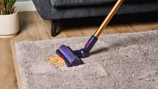 the dyson gen5detect cordless stick vacuum in prussian blue and copper, showing its cleaning head and attachment tools