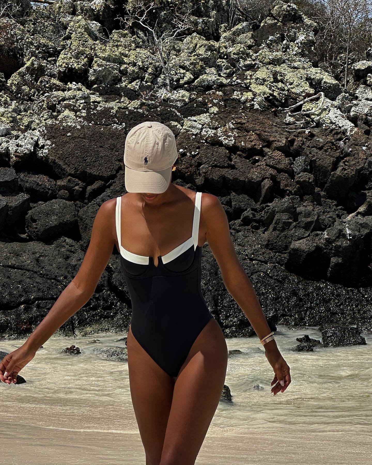 Jas Tookes wears a black and white swimsuit.