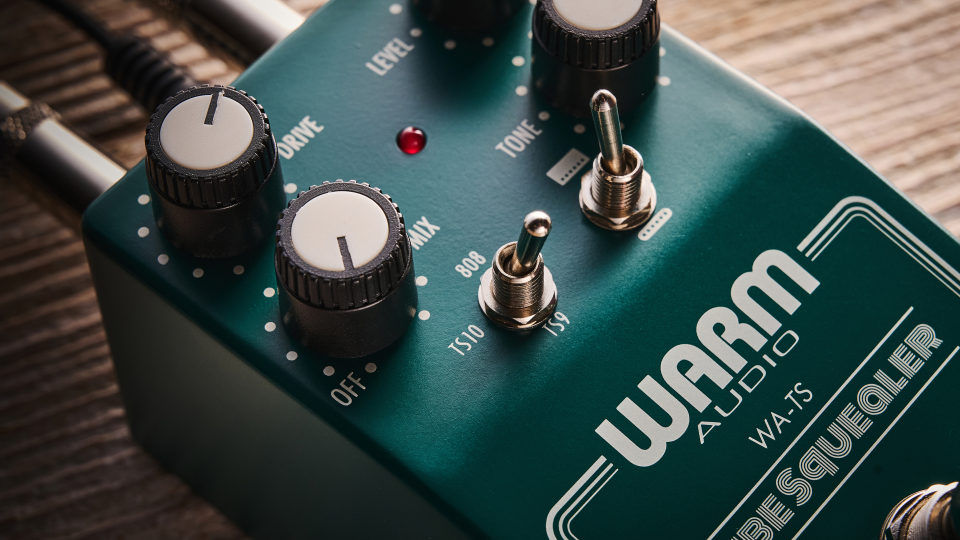Warm Audio Tube Squealer green overdrive pedal shot on wood floorboards