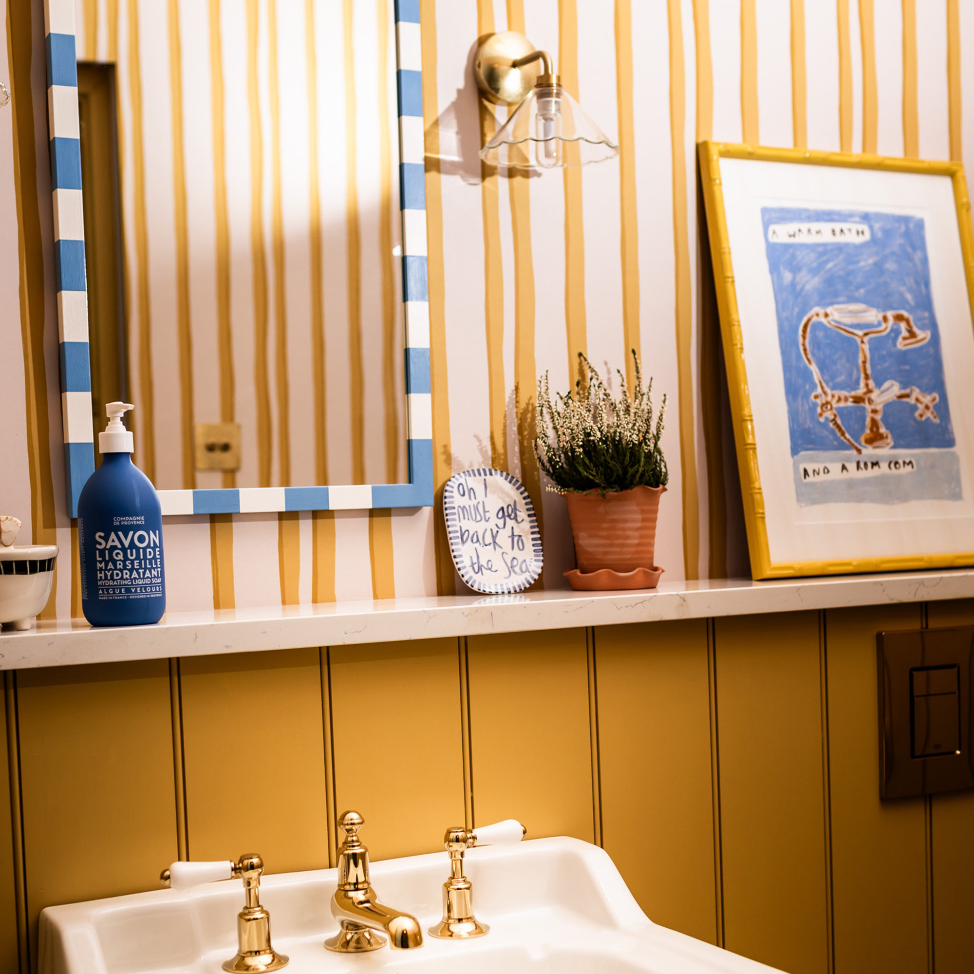 yellow striped bathroom with blue striped mirror