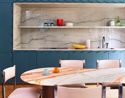 blue kitchen with orange marble dining table and pink chairs