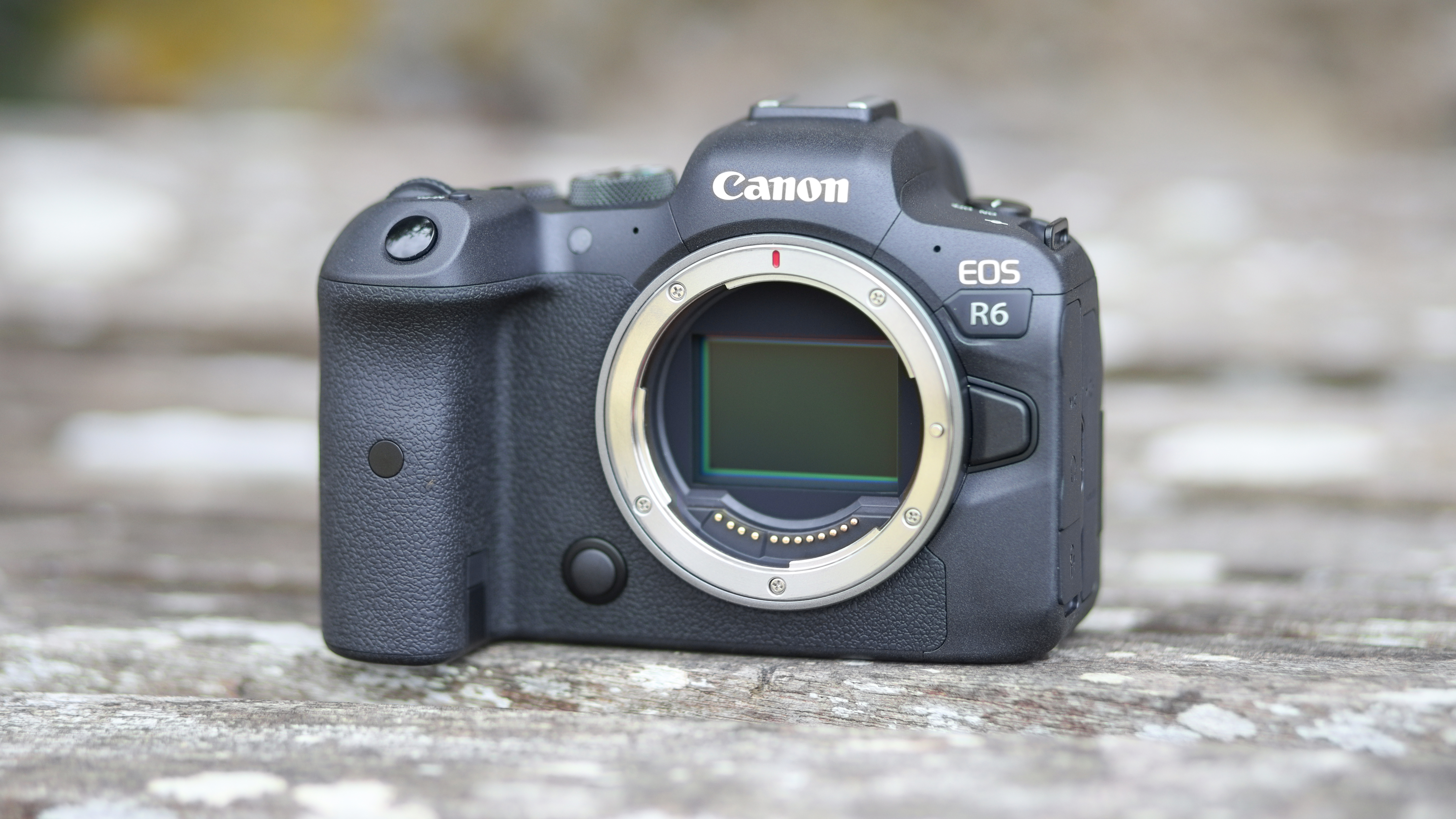 Canon EOS R6, with its sensor exposed, on a wooden surface outdoors