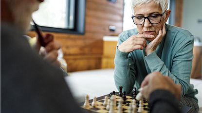 An older, retired couple plays chess.