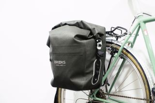 A rounded green pannier mounted to a green bike against a white background