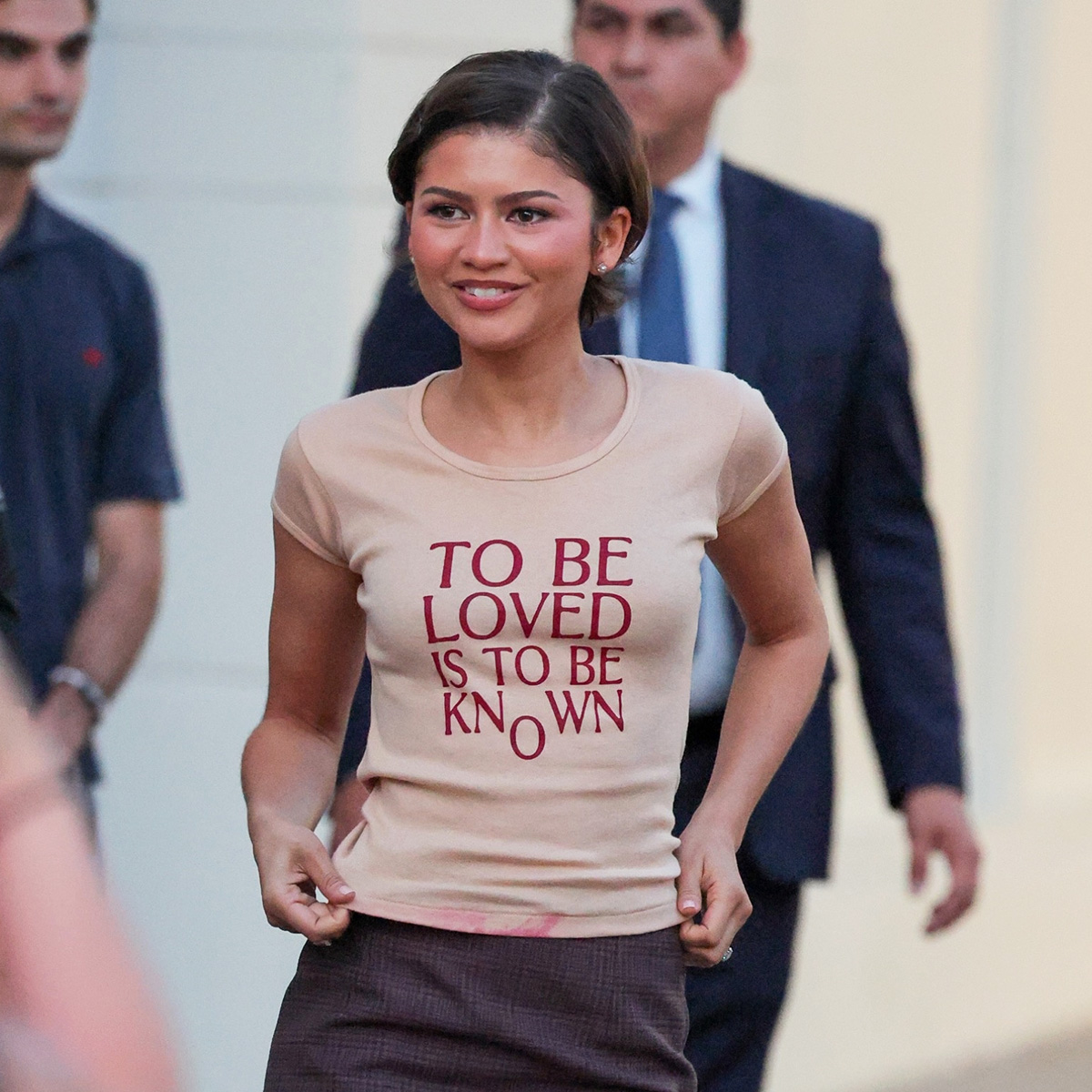 Zendaya wearing a The Drama T-shirt, lace-trim pencil skirt, and red loafers