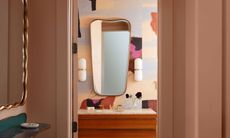 Small powder room with wooden vanity and multicolored abstract wallpaper