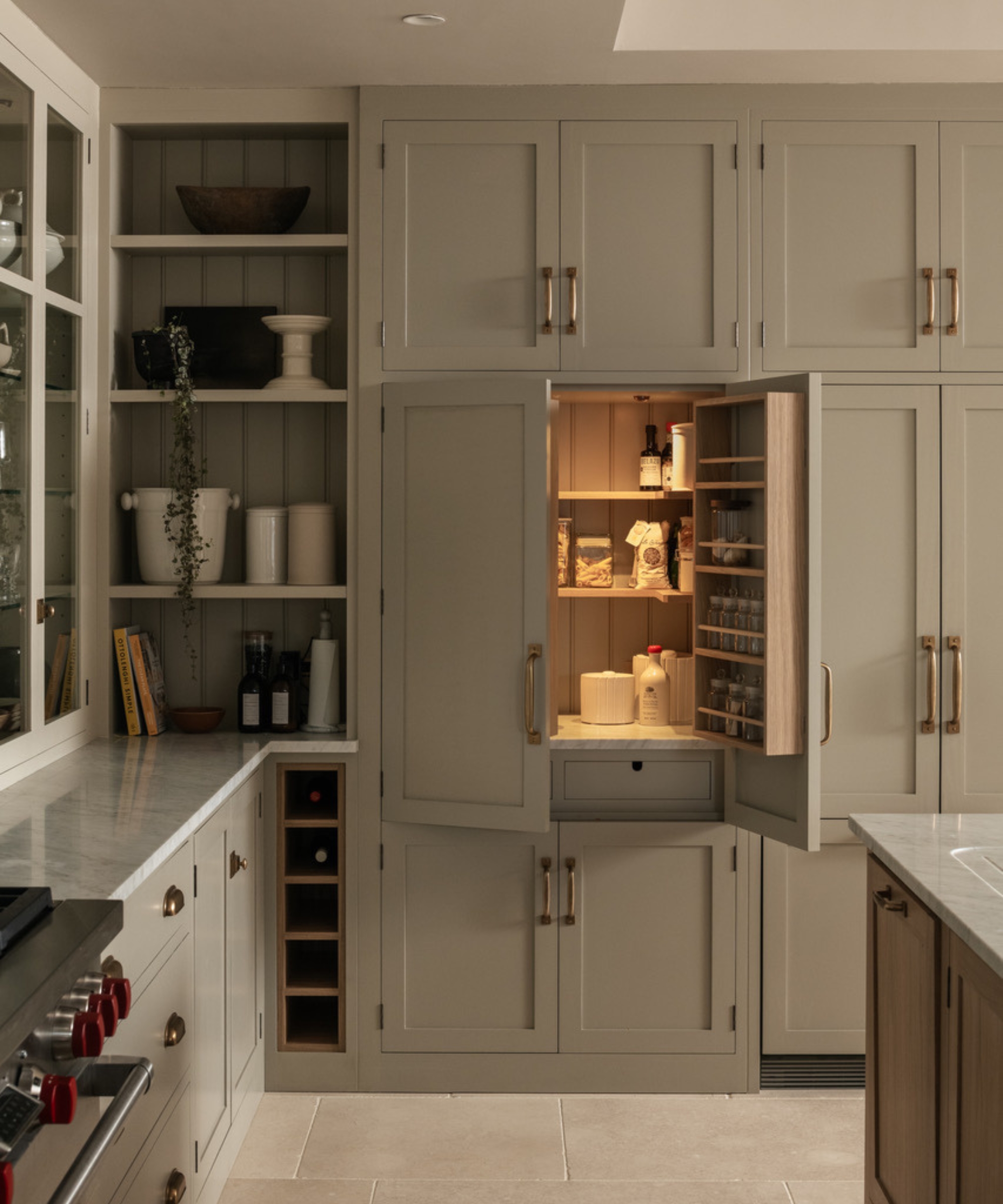 The corner of a green kitchen showing the inside of a hidden pantry