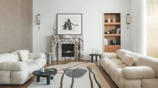 An open plan living area with parquet floor, fireplace with Calacatta Viola marble surround and off-white sofas.