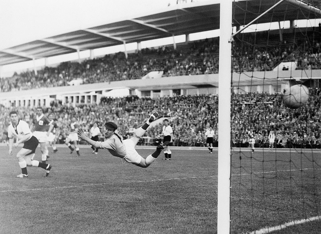 Le gardien de but de l'Irlande du Nord, Harry Gregg, effectue un plongeon gracieux mais rate le ballon alors que Uwe Seeler (non représenté) de l'Allemagne de l'Ouest marque lors du match de football de la Coupe du monde. Ils ont égalisé le match à 2 points chacun. À gauche se trouve Helmut Rahn, de l'Allemagne