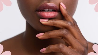 A woman's lower face and hand with pink polygel nails 