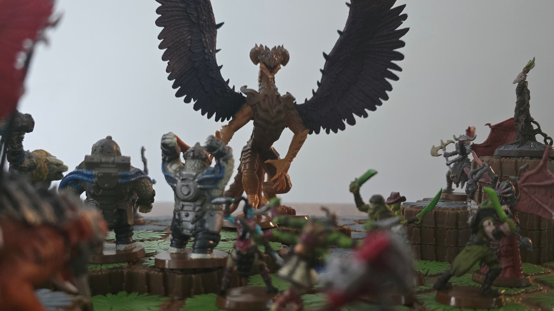 A dragon model with outstretched wings faces down an array of warrior miniatures, all against a white background