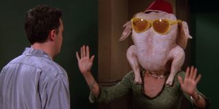 Monica and Chandler in "The One With All The Thanksgivings" dancing with the turkey on her head in Friends.