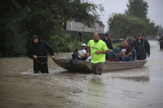 People in Houston walk down a flooded street on Aug. 28, 2017 as Tropical Storm Harvey drives them out of their homes.