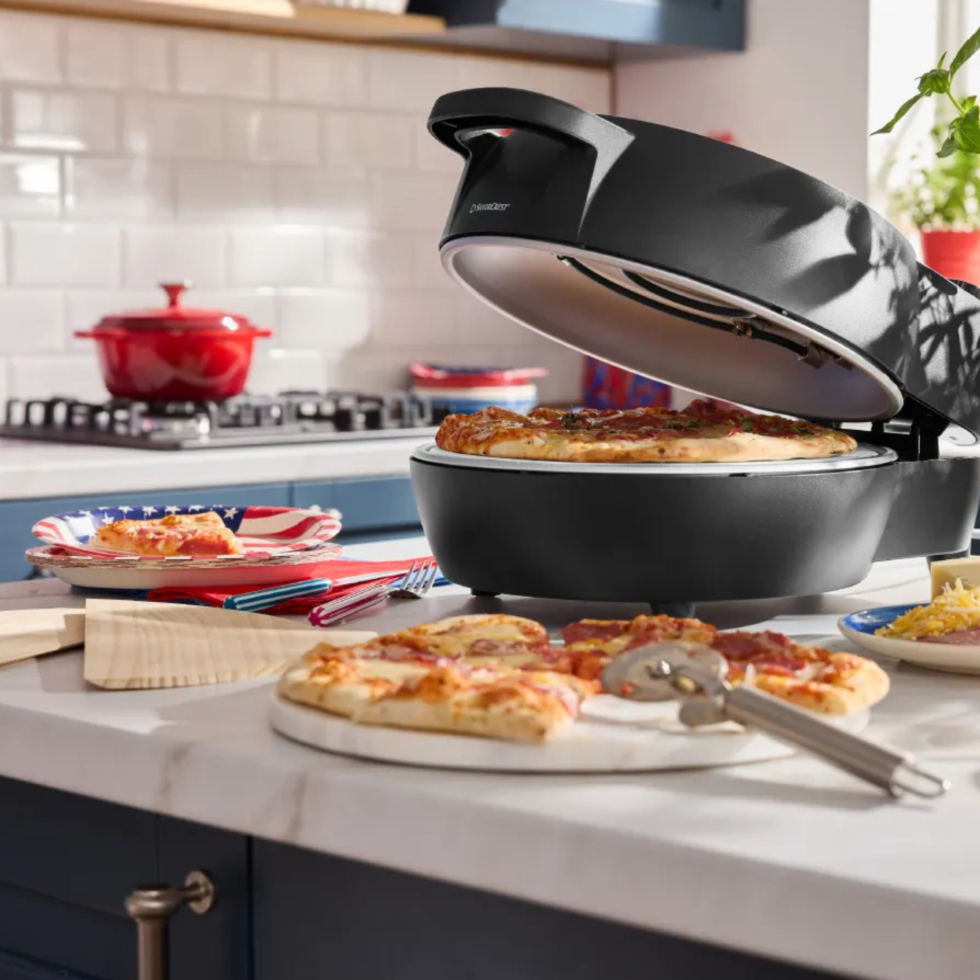 Lidl indoor pizza oven on kitchen island. There is a chopping board with a pizza on top in front.