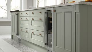 A sage green kitchenwith a marble worktop