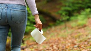 Woman walking with toilet paper in a forest