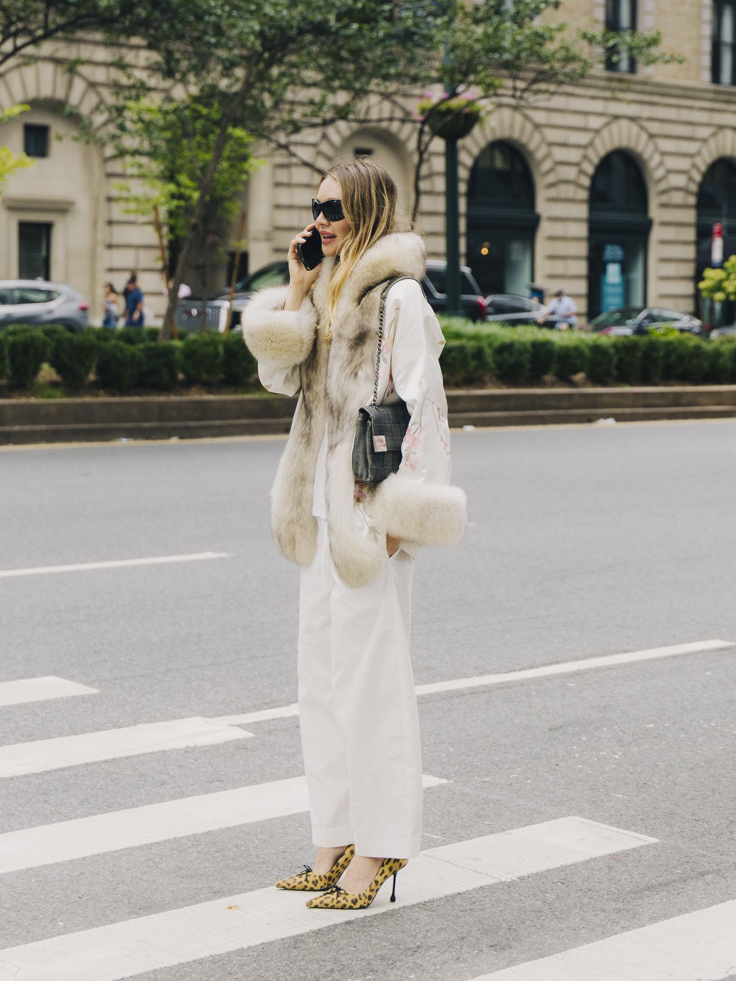 A guest wearing a Conner Ives coat with white pants during New York Fashion Week.