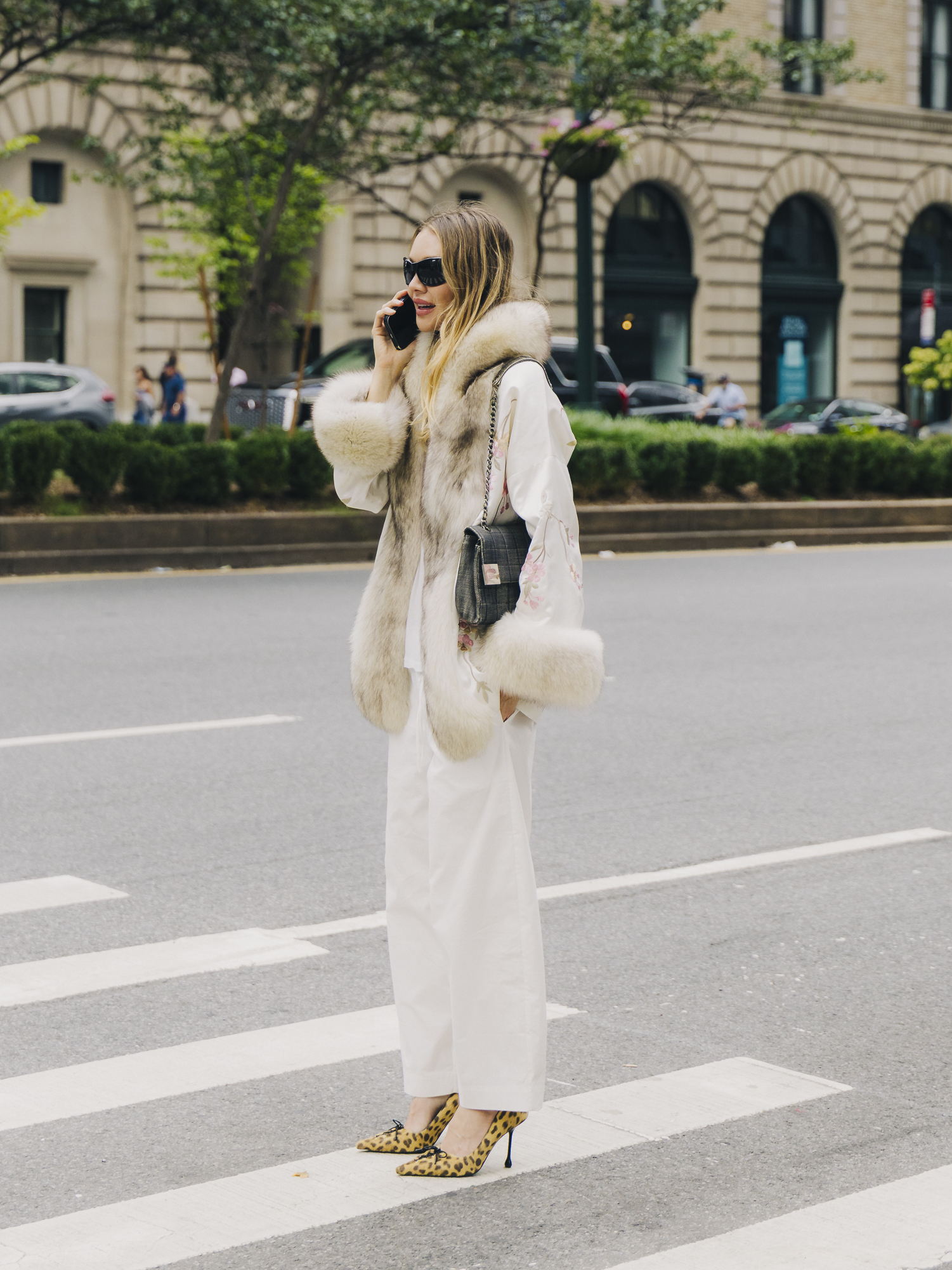 A guest wearing a Conner Ives coat with white pants during New York Fashion Week.
