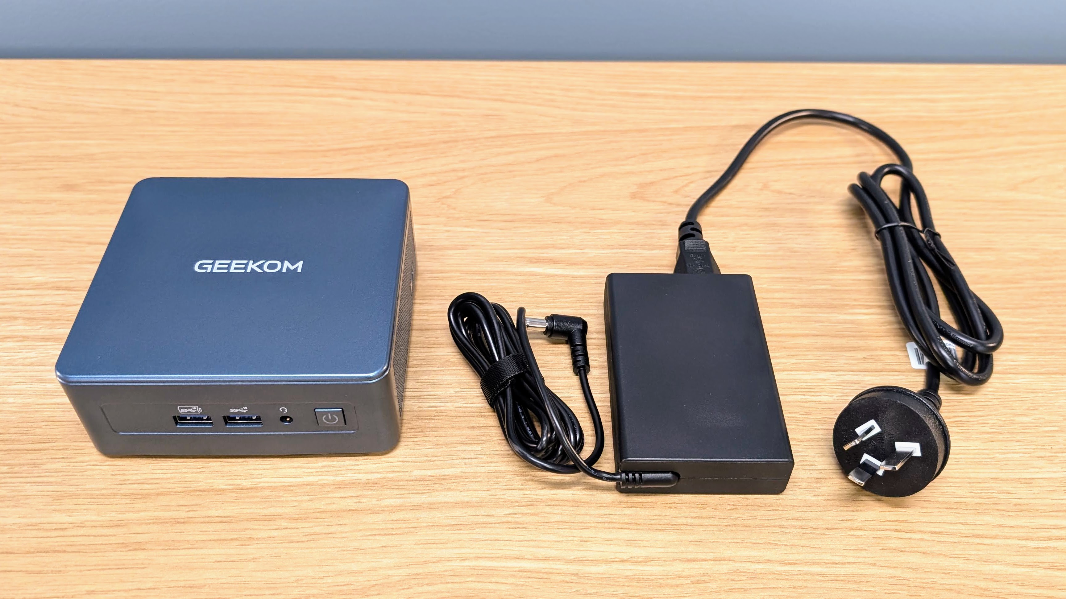 Geekom IT12 mini PC showing size comparison with the power brick