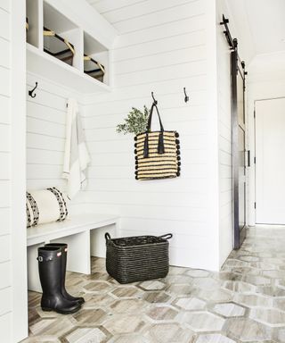 A hallway shoe storage idea with white shiplap walls and open boot bench
