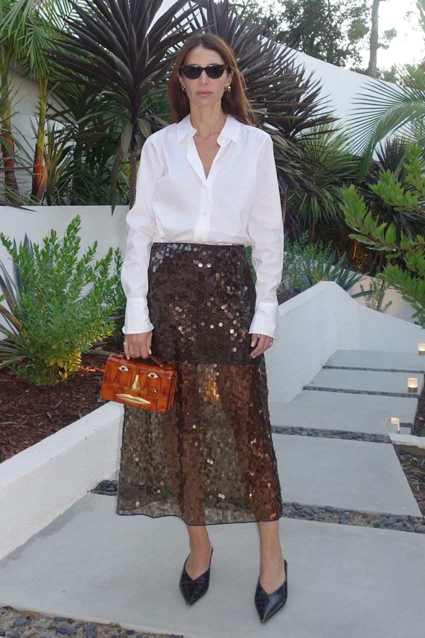 A woman wearing a white button down, sequin skirt, and black heels.