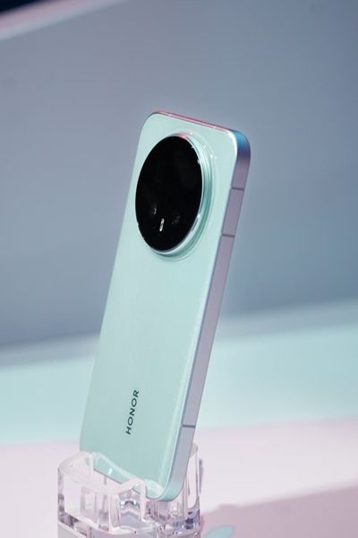 The Honor Magic 8 Pro in a light greenish-blue colorway, showing its rounded, centered camera array during the company's appearance at the Snapdragon Summit 2025 event.