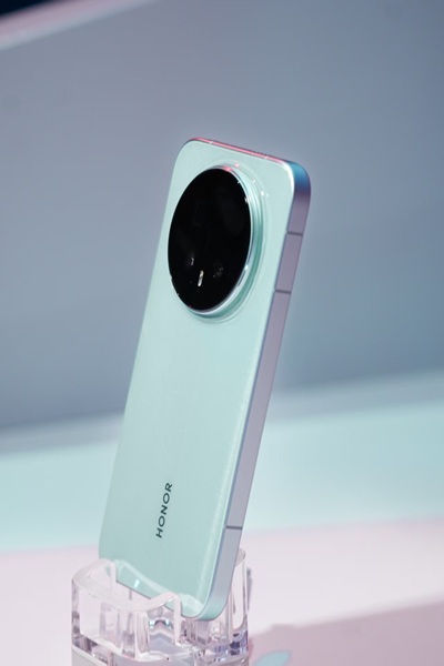 The Honor Magic 8 Pro in a light greenish-blue colorway, showing its rounded, centered camera array during the company's appearance at the Snapdragon Summit 2025 event.