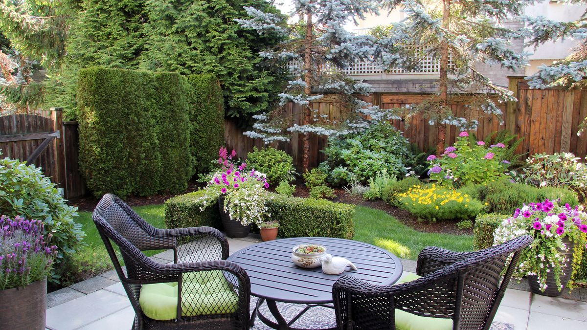 Small yard with outside furniture and tasteful plants around a small lawn